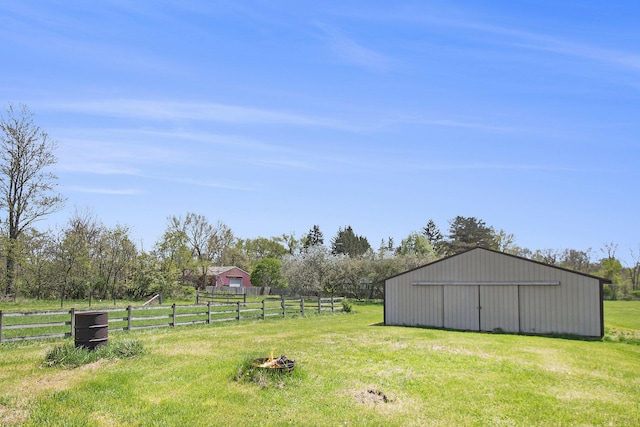 view of yard featuring a garage, a pole building, a fire pit, fence, and an outbuilding