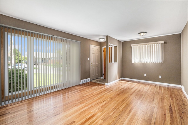 spare room with baseboards, visible vents, and wood finished floors