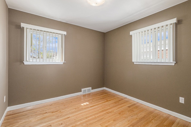empty room featuring baseboards, visible vents, and wood finished floors