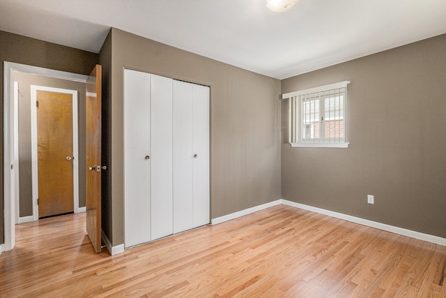 unfurnished bedroom with light wood finished floors, a closet, and baseboards