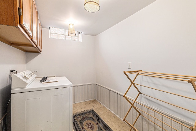 washroom with a wainscoted wall, separate washer and dryer, and cabinet space