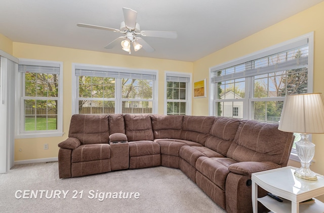 living area featuring light colored carpet, baseboards, and ceiling fan