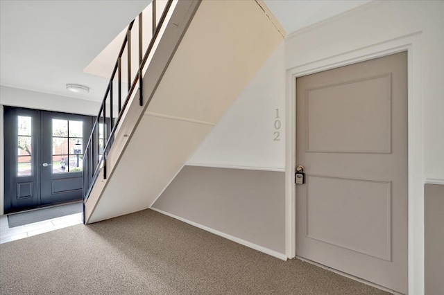 foyer featuring light colored carpet, stairway, and baseboards