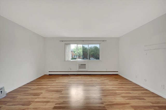 spare room with light wood finished floors, baseboard heating, baseboards, and an AC wall unit