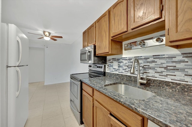 kitchen featuring stainless steel appliances, a sink, a ceiling fan, and decorative backsplash