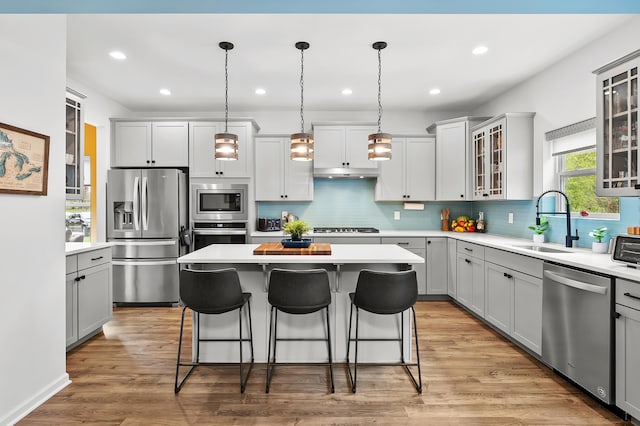 5849 Gavin Ln, Kalamazoo, MI 49009 - kitchen with a breakfast bar area, a center island, a sink, stainless steel appliances, and gray cabinets