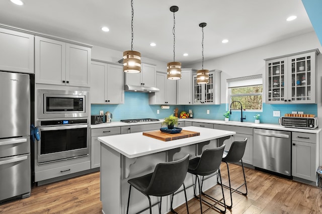 5849 Gavin Ln, Kalamazoo, MI 49009 - kitchen with stainless steel appliances, a kitchen breakfast bar, backsplash, light countertops, and a center island