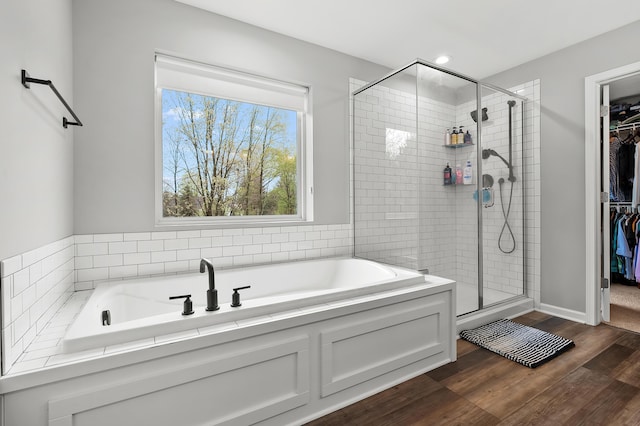 5849 Gavin Ln, Kalamazoo, MI 49009 - full bathroom featuring a stall shower, a spacious closet, a bath, and wood finished floors