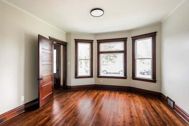unfurnished room with ornamental molding, plenty of natural light, and dark wood finished floors