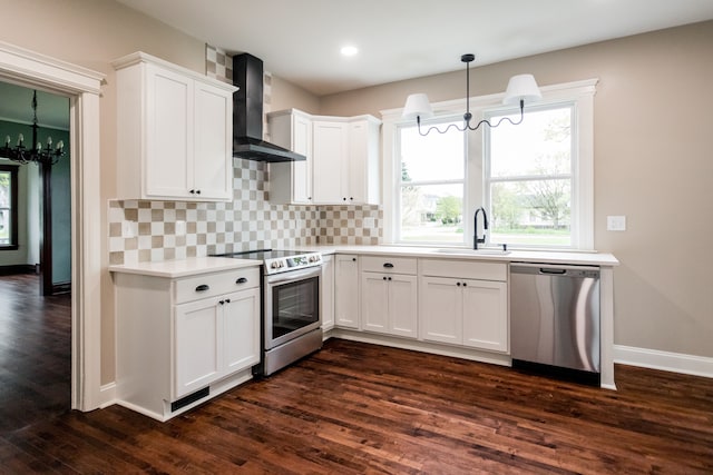 kitchen featuring a sink, wall chimney exhaust hood, stainless steel appliances, a notable chandelier, and dark wood-style floors