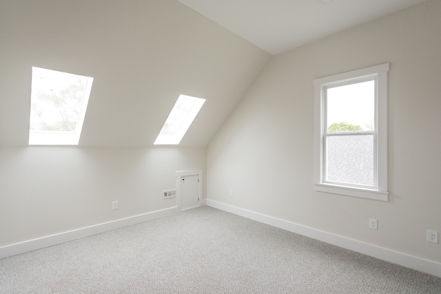 bonus room featuring lofted ceiling with skylight, baseboards, carpet flooring, and visible vents