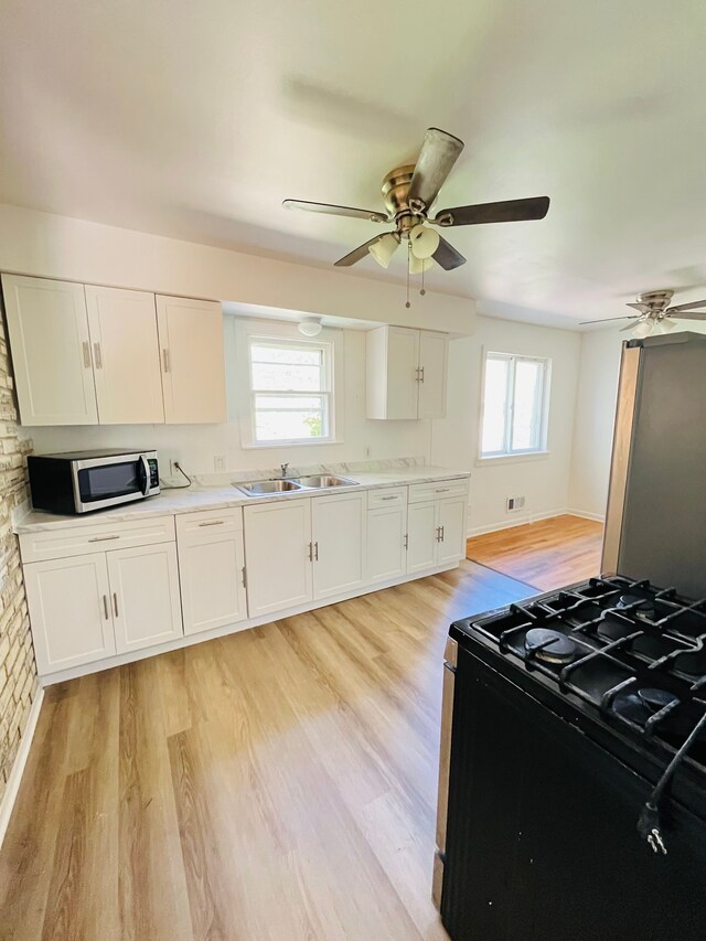 6507 Dupont St, Flint, MI 48505 - kitchen featuring stainless steel microwave, black gas stove, ceiling fan, and light wood-type flooring