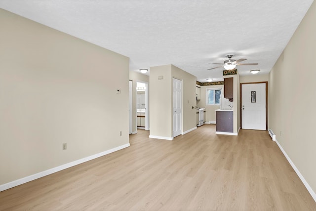 2703 Green Meadows Dr, Traverse City, MI 49685 - unfurnished living room featuring light wood finished floors, a ceiling fan, baseboards, and a sink