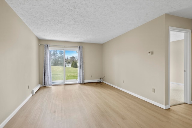 2703 Green Meadows Dr, Traverse City, MI 49685 - empty room with light wood-style flooring, baseboard heating, baseboards, and a textured ceiling