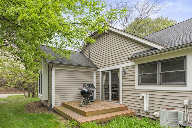 back of house featuring roof with shingles, a deck, and cooling unit
