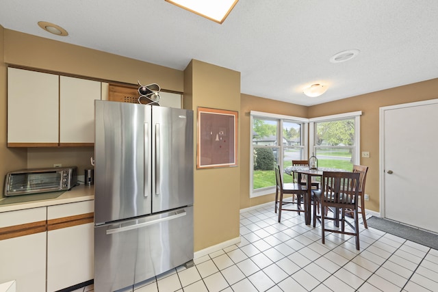 kitchen with freestanding refrigerator, baseboards, light countertops, and a toaster