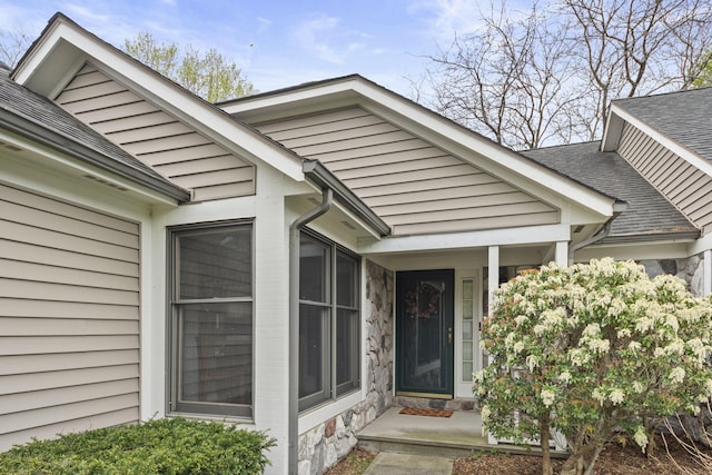 property entrance featuring stone siding and a shingled roof