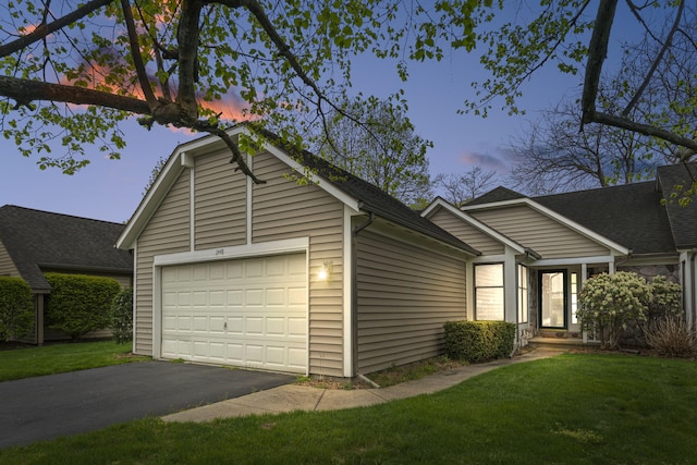 view of front of home with roof with shingles, a lawn, and aphalt driveway