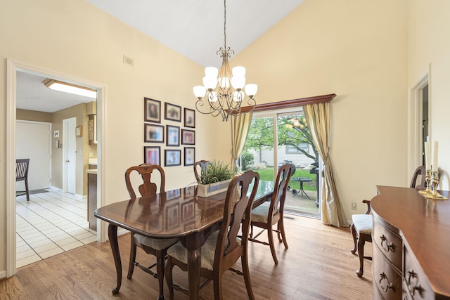 dining room featuring an inviting chandelier, wood finished floors, baseboards, and high vaulted ceiling