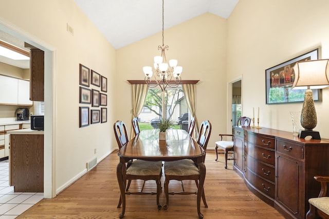dining room featuring light wood finished floors, a chandelier, visible vents, and high vaulted ceiling