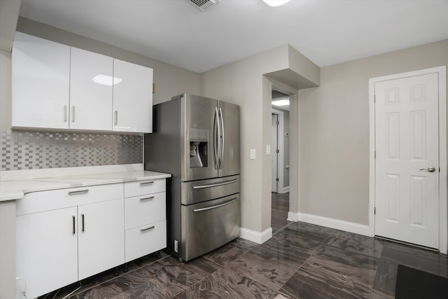 kitchen with stainless steel fridge with ice dispenser, light countertops, decorative backsplash, white cabinets, and baseboards