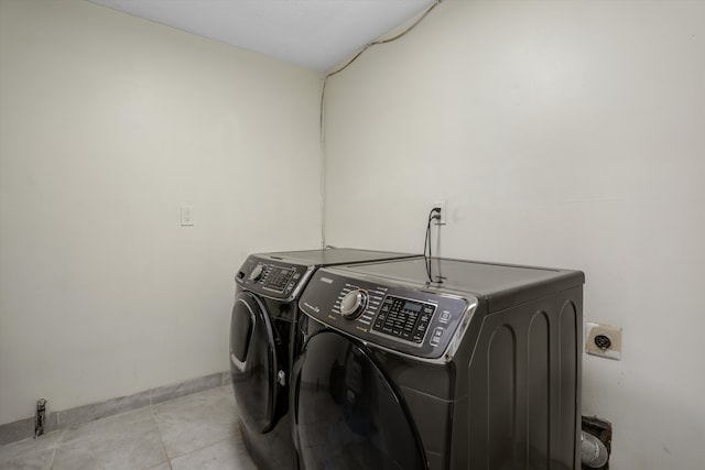 washroom featuring washer and dryer, light tile patterned floors, and baseboards