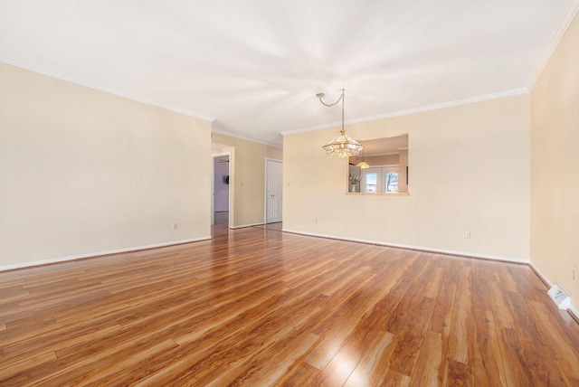empty room with an inviting chandelier, wood finished floors, baseboards, and ornamental molding