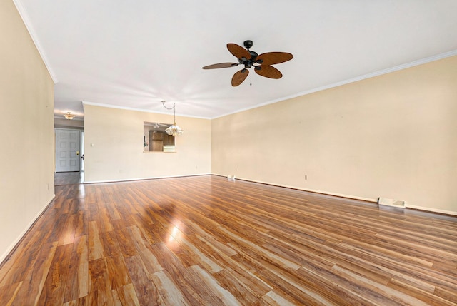 spare room with crown molding, wood finished floors, and ceiling fan