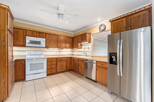 kitchen with a sink, stainless steel appliances, brown cabinetry, crown molding, and light countertops