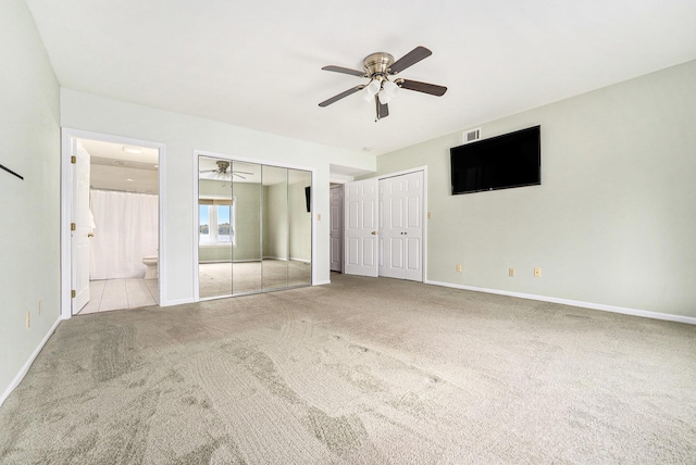 unfurnished bedroom with carpet, two closets, visible vents, baseboards, and ensuite bath