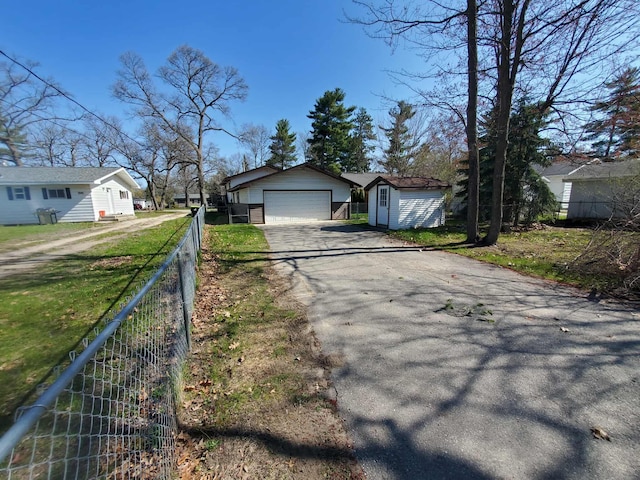 854 Kelley St, Traverse City, MI 49686 - view of front of house with an outdoor structure, asphalt driveway, fence, an attached garage, and a shed
