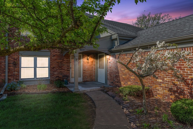 2658 Williamsburg Cir Unit 47, Auburn Hills, MI 48326 - exterior entry at dusk featuring a shingled roof and brick siding