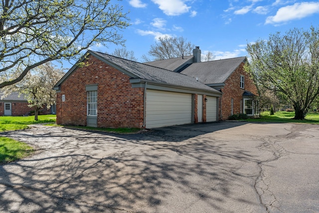 2658 Williamsburg Cir Unit 47, Auburn Hills, MI 48326 - view of side of property with asphalt driveway, brick siding, a garage, and a chimney