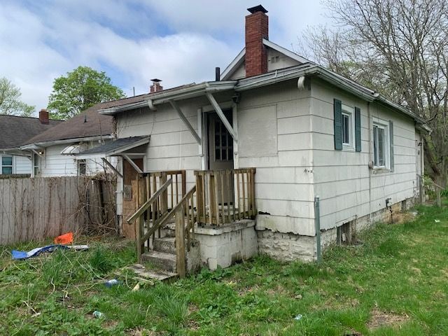 back of house featuring a chimney and fence