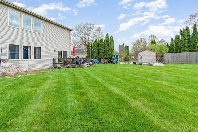 view of yard with a fenced backyard, a deck, and a playground
