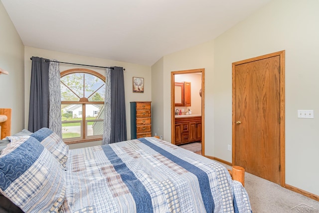 bedroom with light colored carpet, ensuite bath, vaulted ceiling, and baseboards