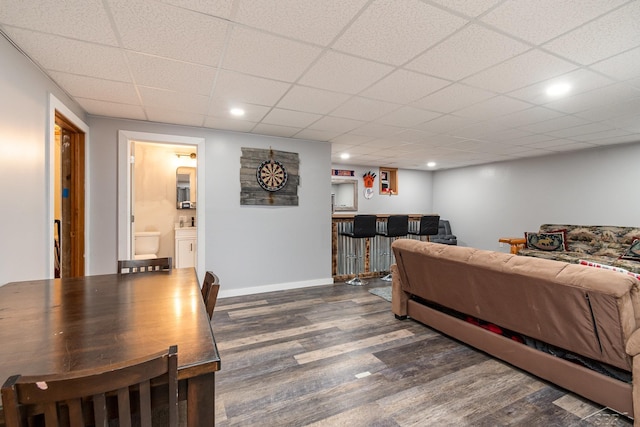 living area with a bar, recessed lighting, baseboards, wood finished floors, and a paneled ceiling