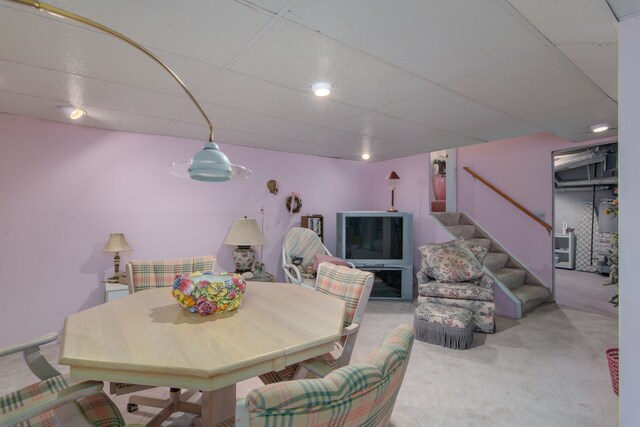 dining area with stairs, carpet flooring, and a drop ceiling