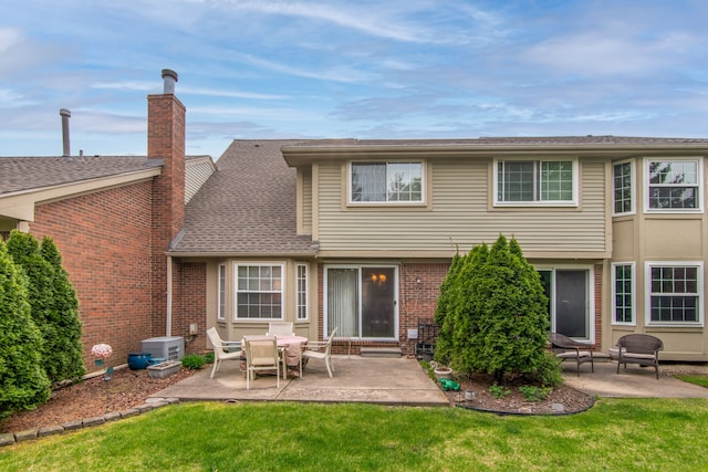 back of property with a lawn, a patio area, brick siding, and a chimney