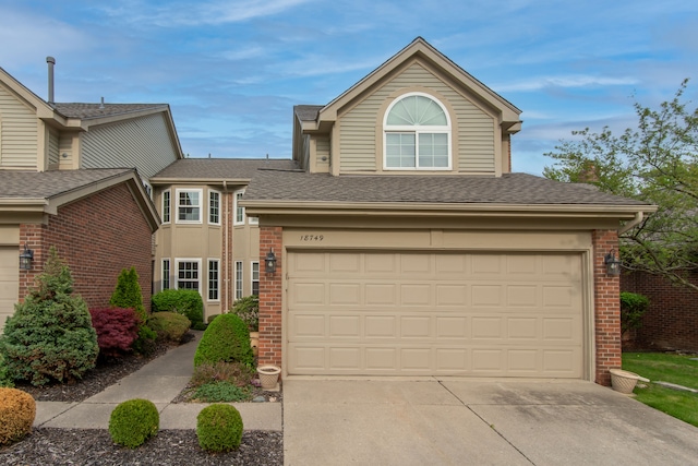 traditional home with concrete driveway, brick siding, roof with shingles, and an attached garage