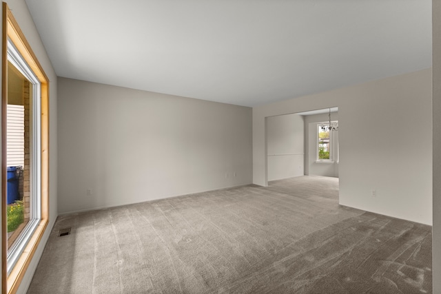 carpeted spare room featuring a chandelier