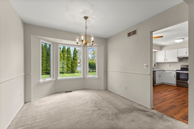 unfurnished dining area featuring dark carpet, a chandelier, and baseboards