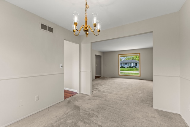 unfurnished room with carpet flooring, a chandelier, and baseboards