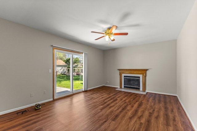 unfurnished living room with ceiling fan, a fireplace with flush hearth, dark wood-style flooring, and baseboards