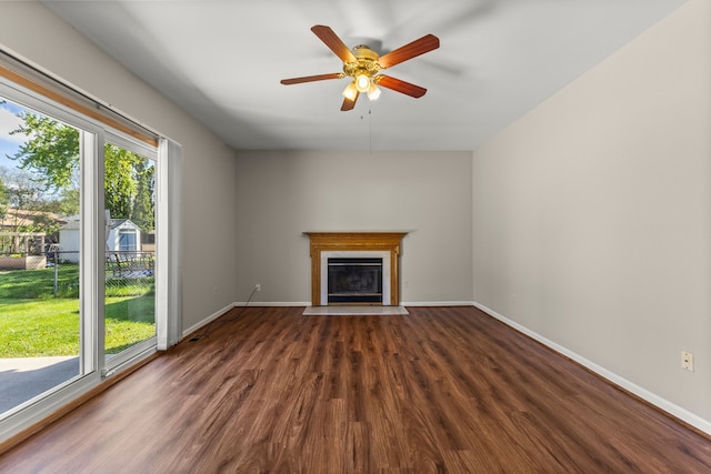 unfurnished living room with wood finished floors, a fireplace with flush hearth, baseboards, and ceiling fan