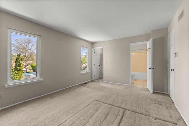 unfurnished bedroom with carpet floors, baseboards, ensuite bath, and a walk in closet