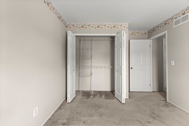 unfurnished bedroom with light colored carpet, a closet, and baseboards