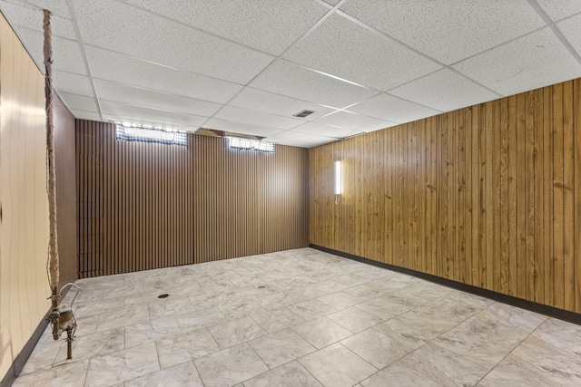 below grade area with wood walls and a paneled ceiling