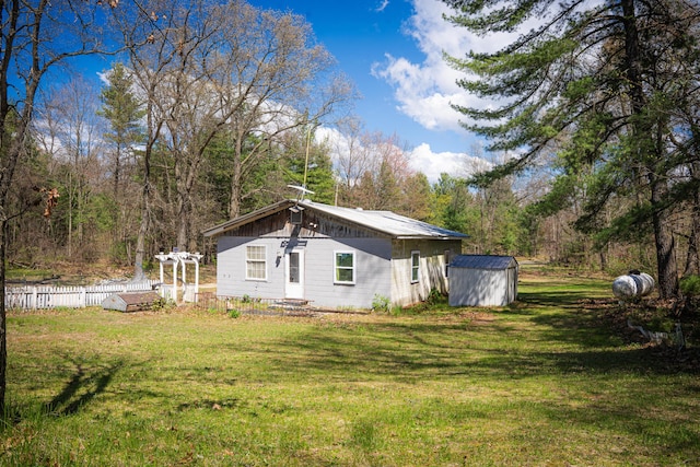5110 Russell Rd, Twin Lake, MI 49457 - back of property with a storage unit, an outbuilding, and a wooded view