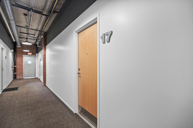 corridor with brick wall, carpet flooring, and baseboards
